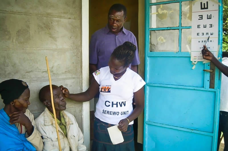 An ophthalmic clinical officer observes a community health worker examining a patient's eyes so that he can offer helpful feedback and support, if needed. Hillary Rono