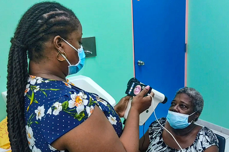 A female member of the eye care team holds a camera in from of a female patient who is sitting down